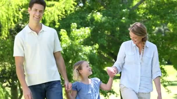 Щасливі батьки зі своєю маленькою дівчинкою в парку — стокове відео