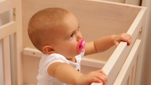 Söt baby flicka stående i sin barnsäng — Stockvideo