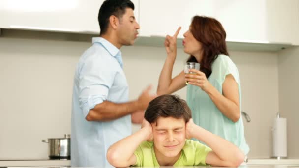 Chico molesto cubriéndose las orejas mientras sus padres pelean — Vídeo de stock