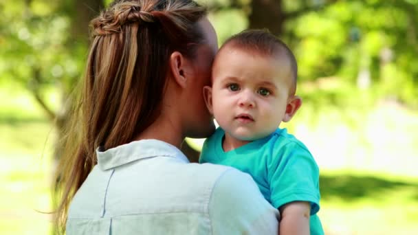 Madre sosteniendo bebé hijo en el parque — Vídeos de Stock