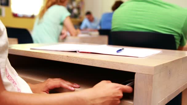 Estudiante usando smartphone debajo del escritorio en clase — Vídeo de stock