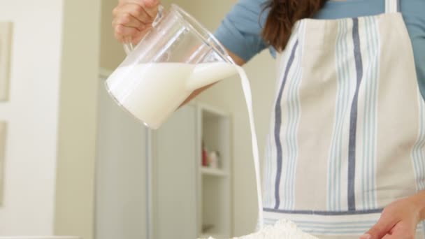 Женщина наливает молоко в миску муки — стоковое видео