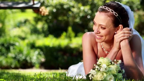 Schöne Braut auf dem Gras liegend — Stockvideo
