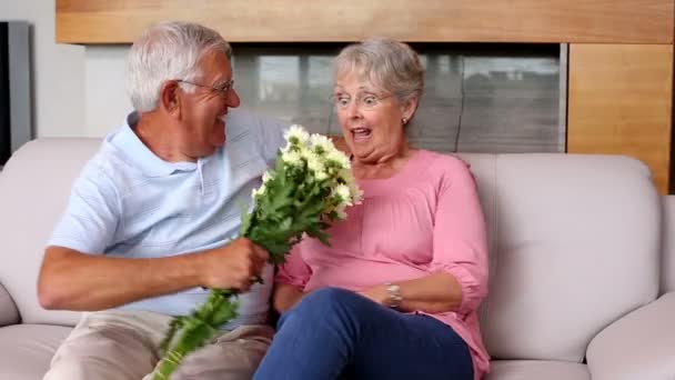 Senior uomo sorprendente partner con fiori sul divano — Video Stock