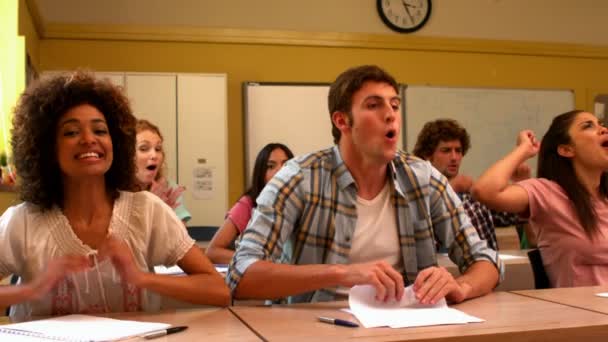 Estudiantes emocionados animando en el aula — Vídeo de stock