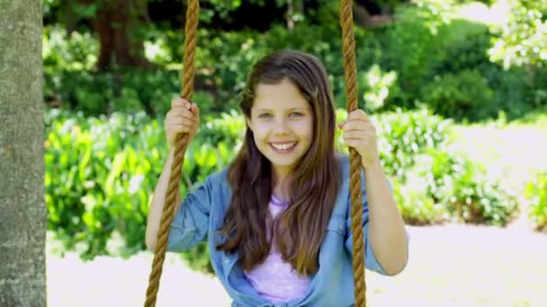 Девушка сидит на качелях в парке — стоковое видео