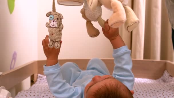 Ребенок играл с мобильным телефоном в кроватке — стоковое видео