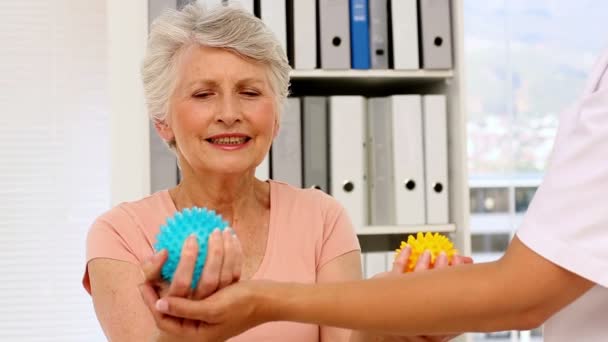 Медсестра показывает пожилым пациентам, как пользоваться массажными шариками — стоковое видео