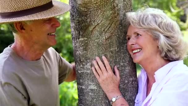 Gepensioneerde paar leunend tegen boom glimlachen bij elkaar — Stockvideo