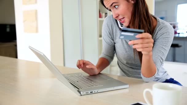 Mooie brunette laptop gebruikt om online te winkelen tijdens het gesprek op de telefoon — Stockvideo