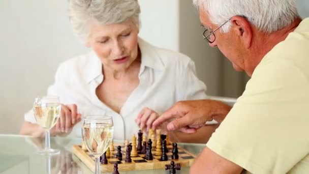 Senior paret sitter vid bord spelar schack — Stockvideo