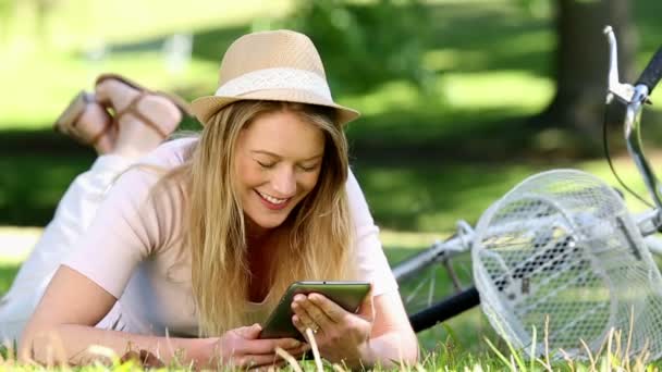 Милая девушка с планшетным компьютером рядом со своим велосипедом в парке — стоковое видео