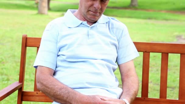 Homem aposentado dormindo em um banco de parque — Vídeo de Stock