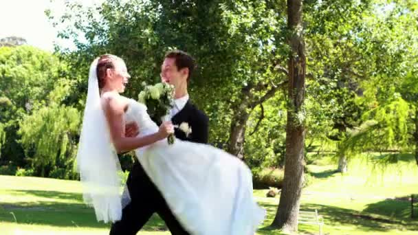 Groom pegando sua esposa bonita novo no parque — Vídeo de Stock