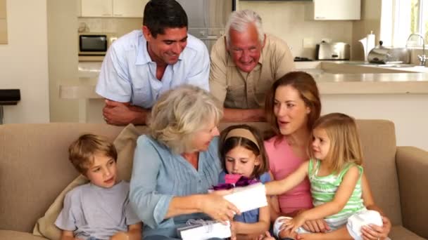 Abuela recibiendo regalos de sus nietos en el sofá — Vídeo de stock