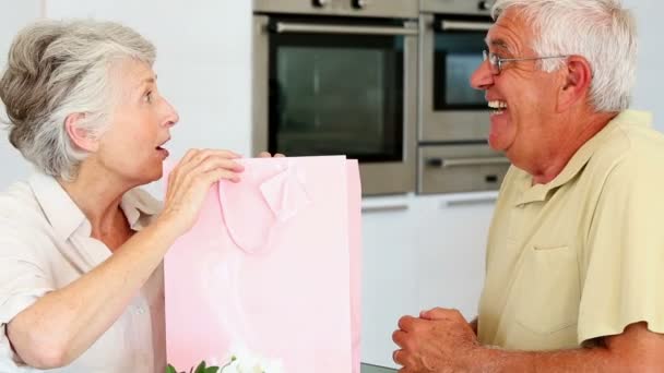 Старший мужчина дарит своему партнеру подарок в розовой сумке — стоковое видео