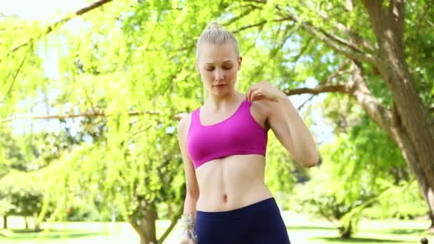 Fit blonde drinking water in the park — Stock Video