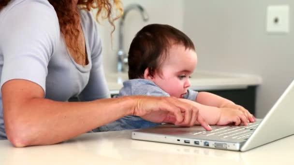 Matka siedzi z dzieckiem na kolanach za pomocą laptopa — Wideo stockowe