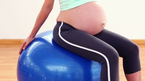 Embarazada rubia sentado en la pelota de ejercicio — Vídeo de stock