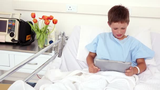 Pequeño niño enfermo sentado en la cama usando tableta pc — Vídeos de Stock