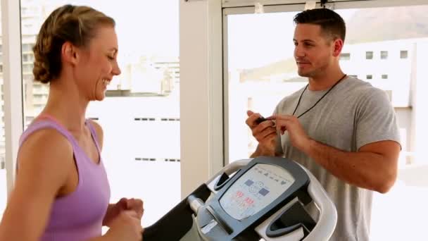 Fit mujer corriendo en la cinta de correr con entrenador cronometrar su — Vídeo de stock