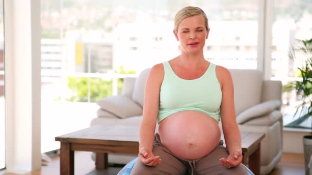 Беременная женщина, сидящая на синем мяче — стоковое видео