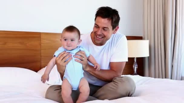 Feliz padre sentado con el bebé hijo en la cama — Vídeos de Stock