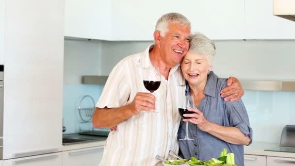 Старшая пара готовит здоровый салат во время питья красного вина — стоковое видео
