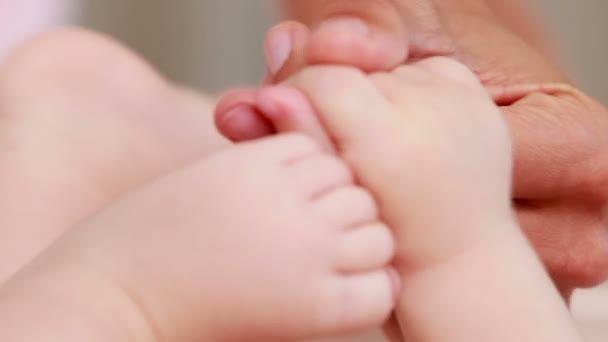 Manos arrugadas sosteniendo las manos del bebé — Vídeo de stock