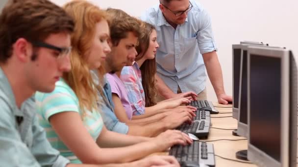 Студенты, работающие в компьютерном классе с преподавателем — стоковое видео