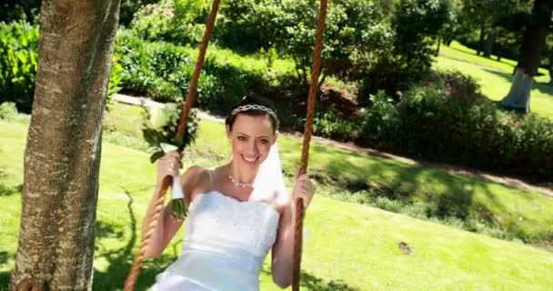 Lachende bruid zittend op een schommel — Stockvideo