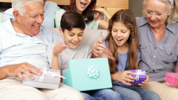 Šťastný rozšířená rodina otevření dárky na gauči — Stock video