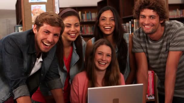 Glada studenter står i biblioteket med laptop — Stockvideo