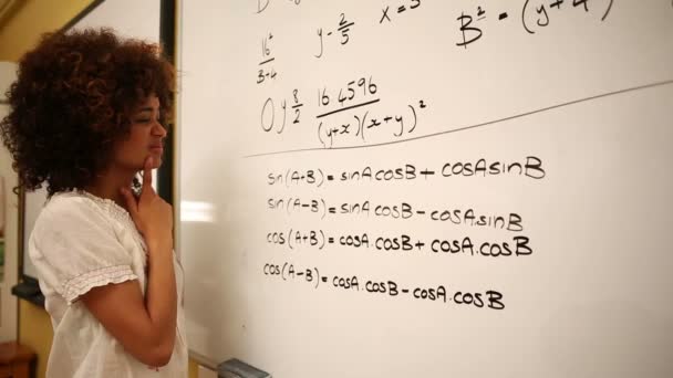 Estudiante confundido mirando matemáticas en pizarra blanca — Vídeo de stock