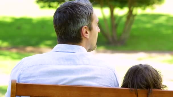 Père et fils assis sur un banc de parc — Video