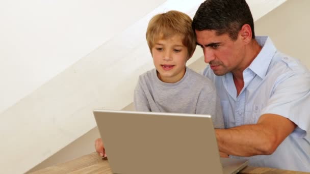 Menino usando laptop com seu pai na mesa — Vídeo de Stock