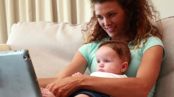 Mor använder TabletPC med baby son i hennes knä — Stockvideo