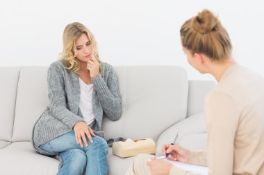 Blonde woman listening to her therapist taking notes clipart
