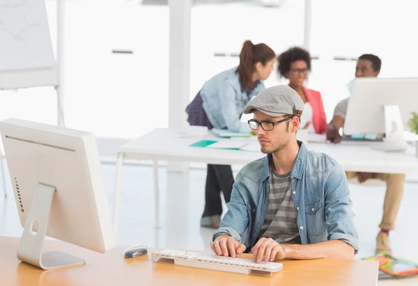 Artiste masculin utilisant l'ordinateur avec des collègues au bureau — Photo