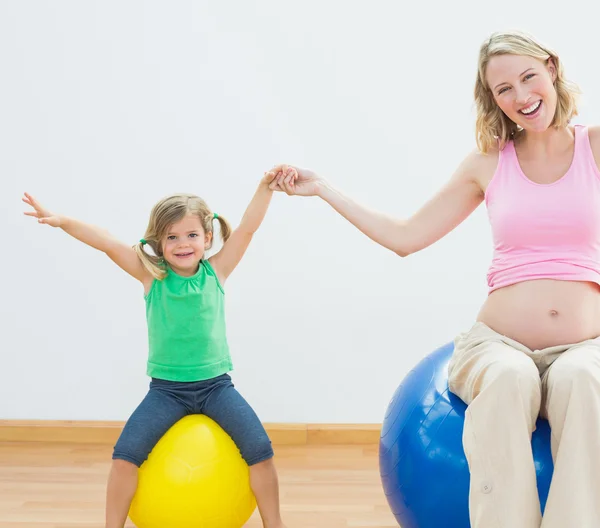 Embarazada mujer en ejercicio pelota con hija — Foto de Stock