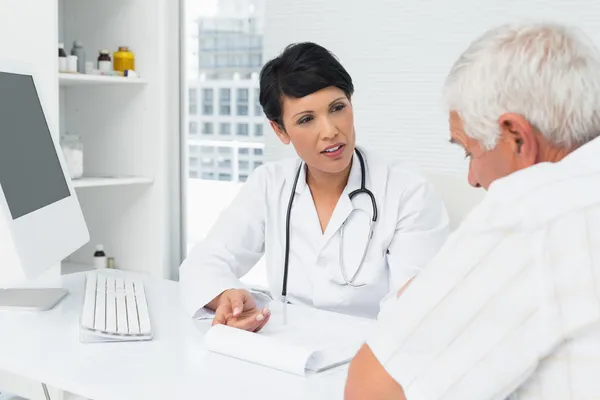 Medico femminile che spiega i rapporti ai pazienti anziani — Foto Stock