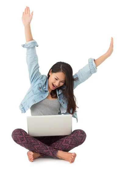 Азиатка аплодирует с ноутбуком, сидящим на полу — стоковое фото