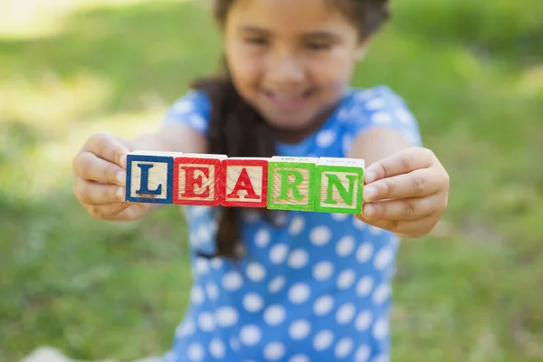 公園で '学ぶ' としてブロック アルファベットを持って幸せな女の子 — ストック写真