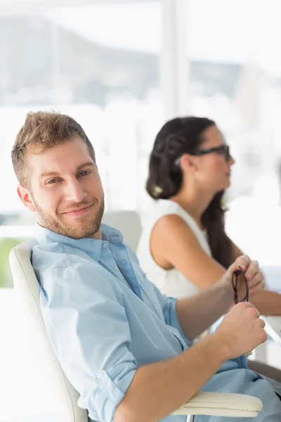 Feliz diseñador sonriendo a la cámara en el escritorio — Foto de Stock