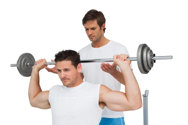 Trainer helpen fit mens op te heffen de barbell bench press — Stockfoto