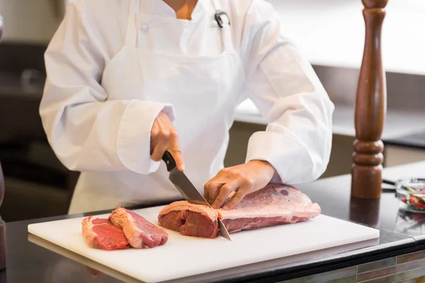 Hands cutting meat in kitchen