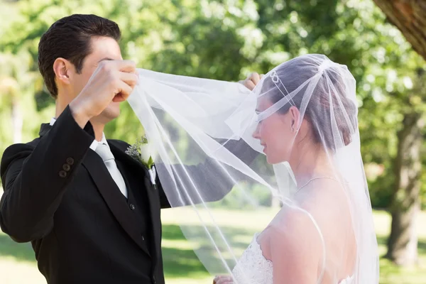 Bahçe içinde sevgi dolu damat örtüsünü açmak gelin — Stok fotoğraf