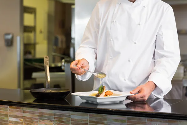 Mid section of a chef garnishing food in kitchen — Stock Photo, Image