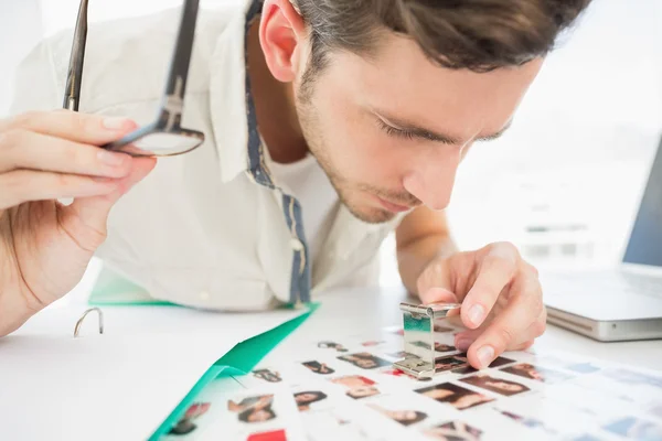 Concentre-se artista masculino sentado na mesa com fotos — Fotografia de Stock