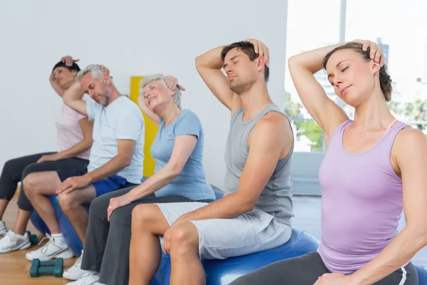 Klassen sitter på träningsbollar och stretching nacken i gym — Stockfoto